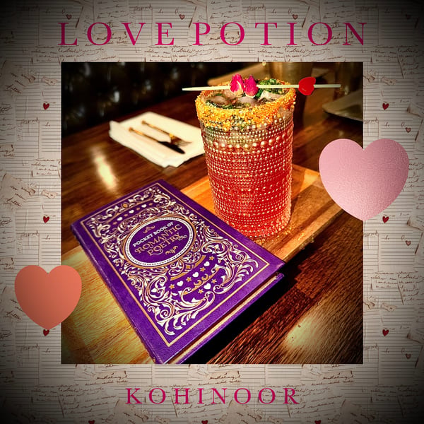 A vibrant red cocktail with a sugared rim and floral garnish sits beside a purple poetry book.