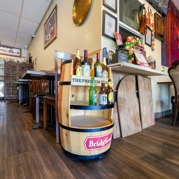 Restaurant interior with a wooden barrel display of beer and wine, and Indian decor.