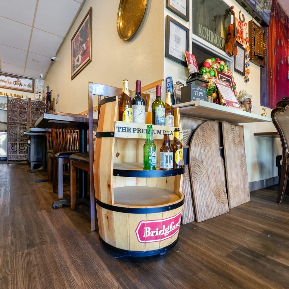 Restaurant interior with a wooden barrel display of beer and wine, and Indian decor.