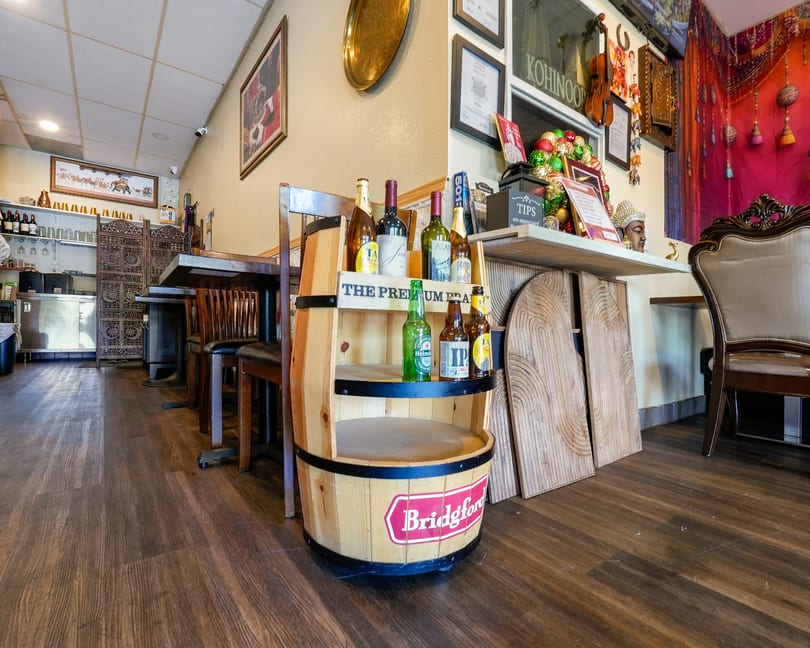 Restaurant interior with a wooden barrel display of beer and wine, and Indian decor.