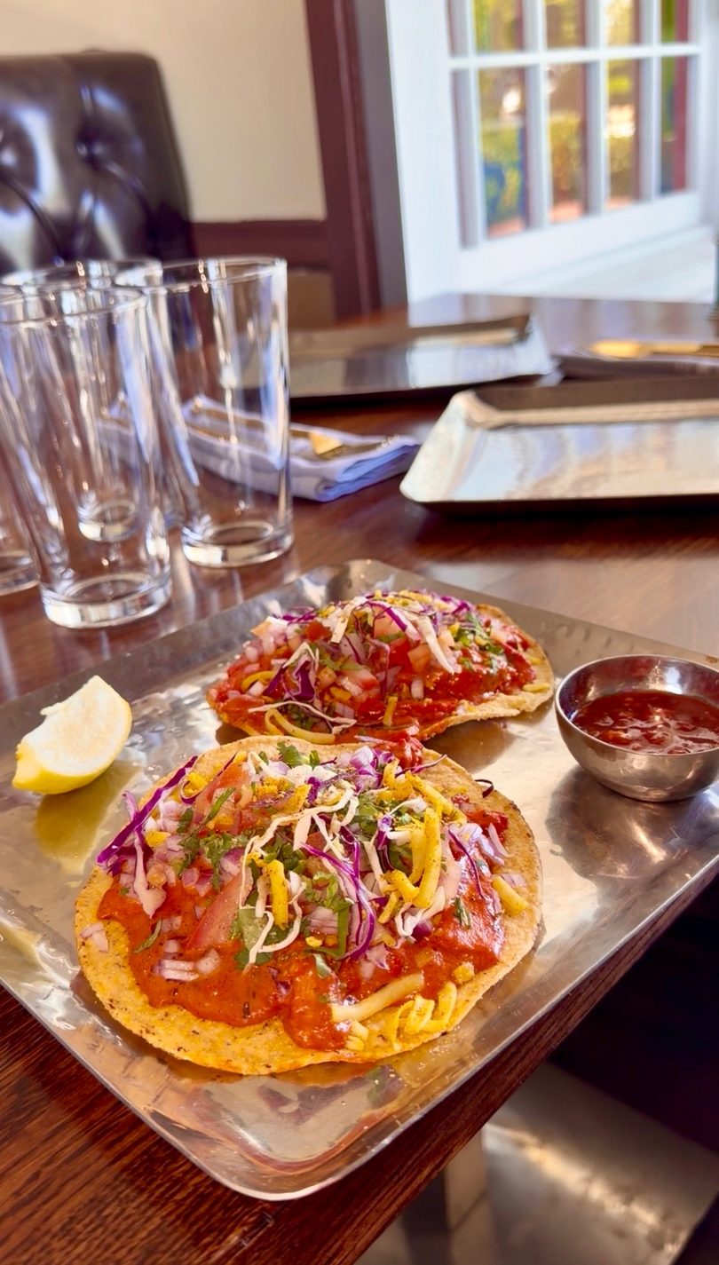Two vibrant tostadas with red sauce, shredded cabbage, and cheese, served with a lemon wedge and salsa.